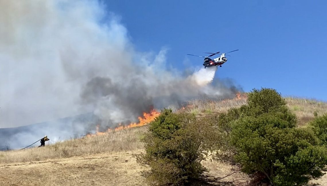 A Ventura County firefighter and helicopter fighting the Sandy Fire on May 18, 2026. (Wikipedia)